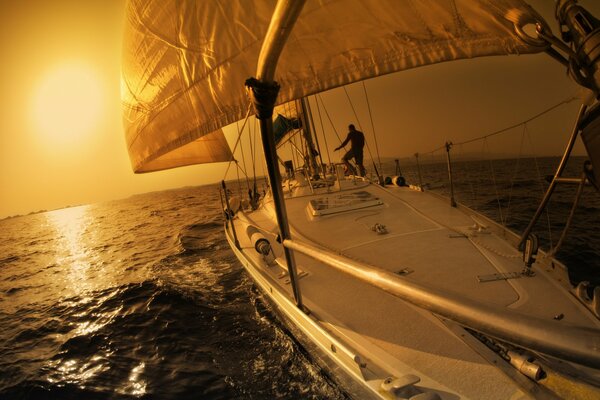 A man on a sailboat in the open sea and sunset