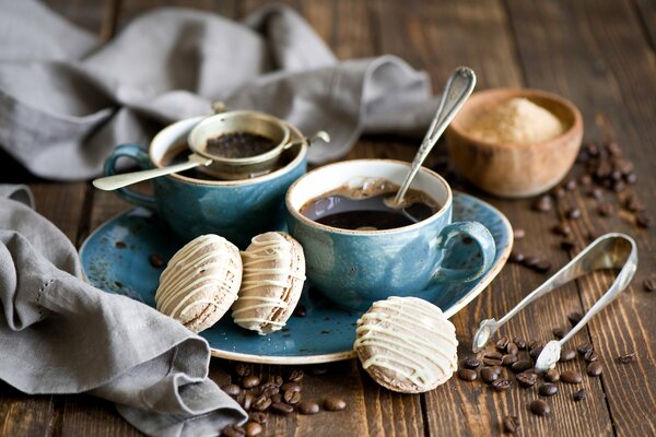 Par de tazas de café con macarrones y granos de café