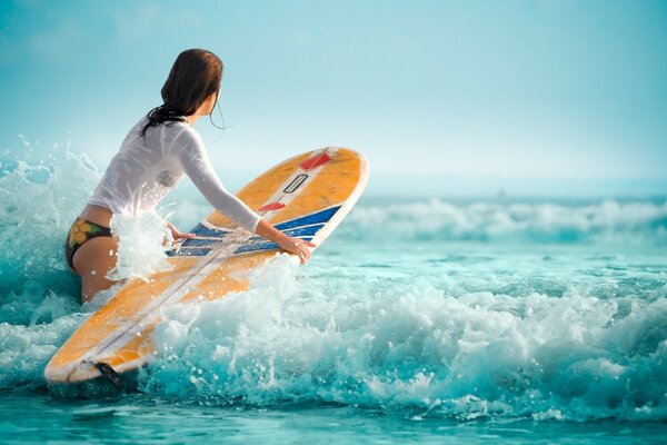 The picture shows waves, the ocean, a girl who knows a lot about sports