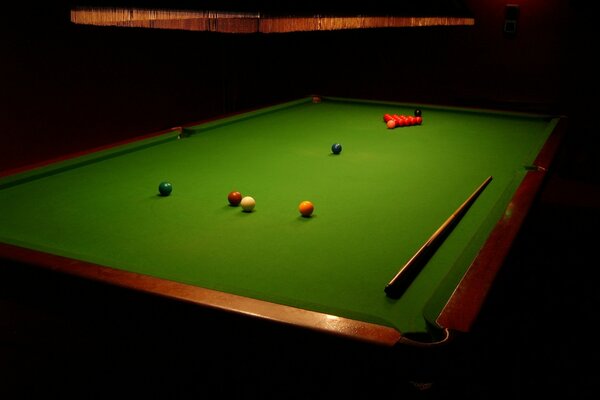 Billiard table with balls and cue under the lamp