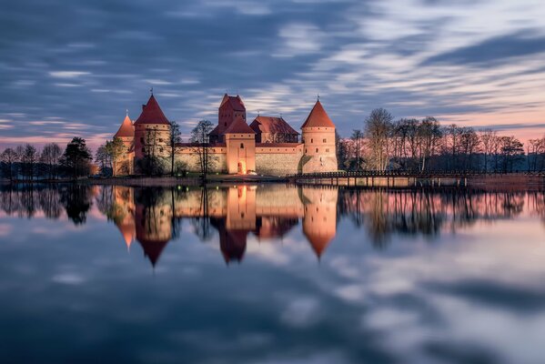 Litwa zamek odbija się w vodda o zachodzie słońca