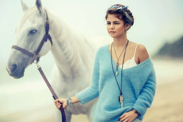 A girl walks with a horse on a sea beach