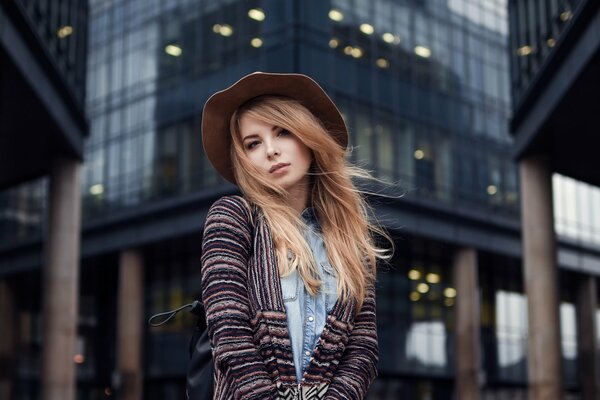 A girl in a hat on the background of buildings