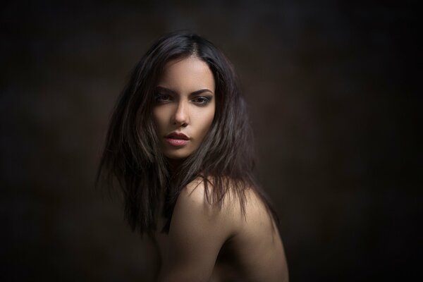 Naked brown-eyed girl on a dark background