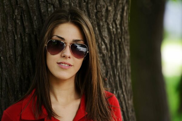 Chica de pelo oscuro debajo de la madera en gafas de color oscuro