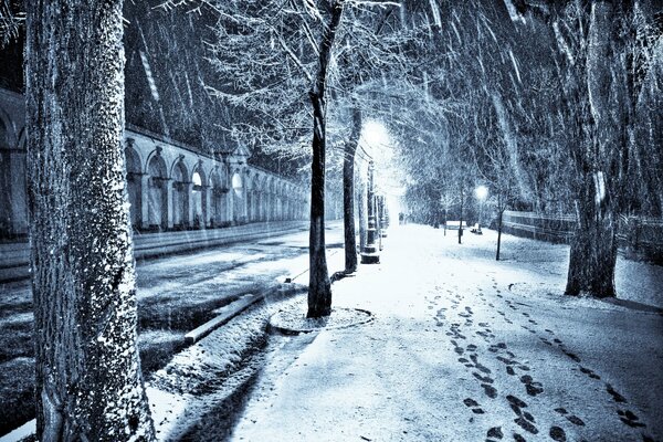 Snow-covered alley at night in the light of lanterns