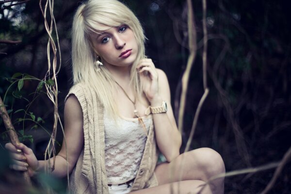 A girl with a watch on her hand is holding on to a branch