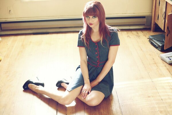 A girl in a dress is sitting on the floor