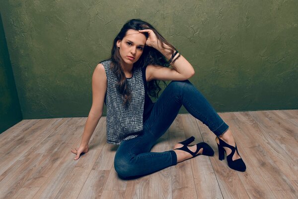 A girl in jeans is sitting on the floor