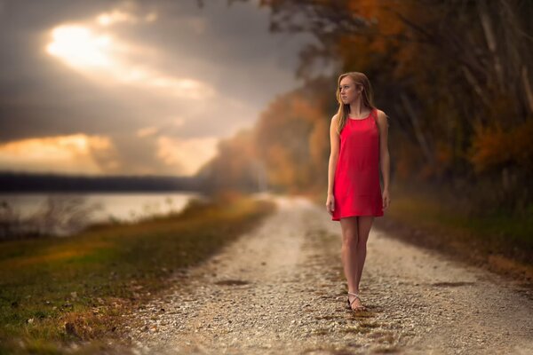 Süßes Mädchen im Kleid auf der Straße im Herbst