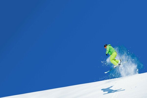 Прыжок на лыжах спортсмена. Яркий снег и голубое небо
