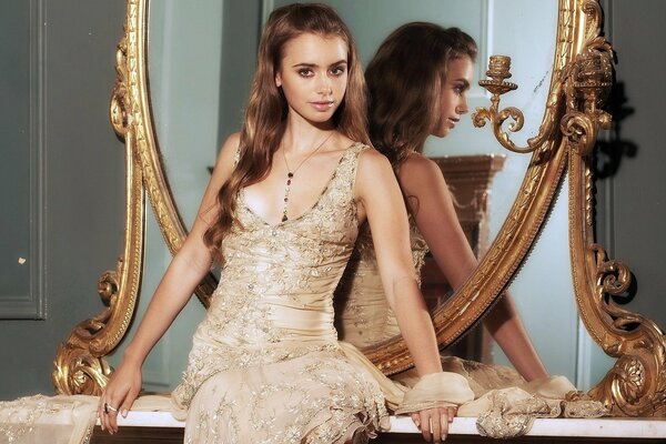 A girl in a lace dress stands at the mirror