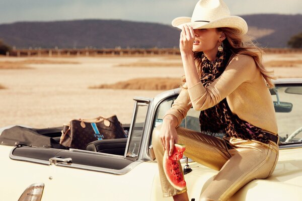 Sitting on the hood of a convertible model in a cowboy hat