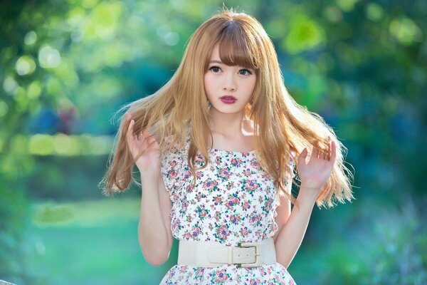 A girl in a flower-patterned dress straightens her blonde hair