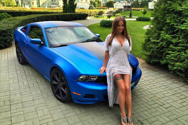 Beautiful girl on the background of a blue Ford Mustang