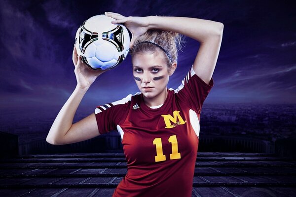 A girl in a football uniform with a ball