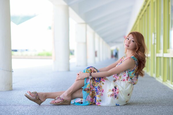 A beautiful Asian woman is sitting on the asphalt