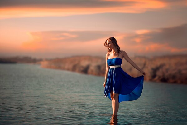 Mädchen im blauen Kleid steht im Wasser