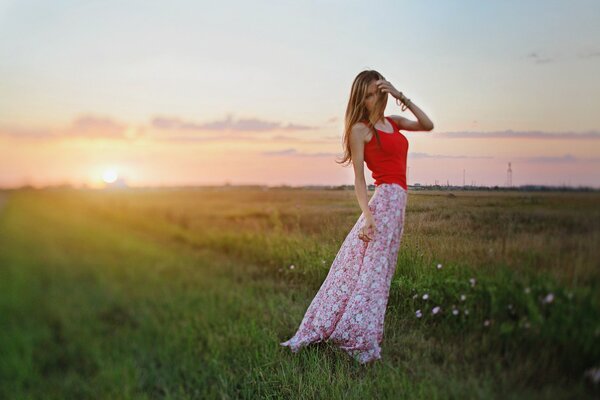 Chica en una falda larga en el fondo de la puesta de sol