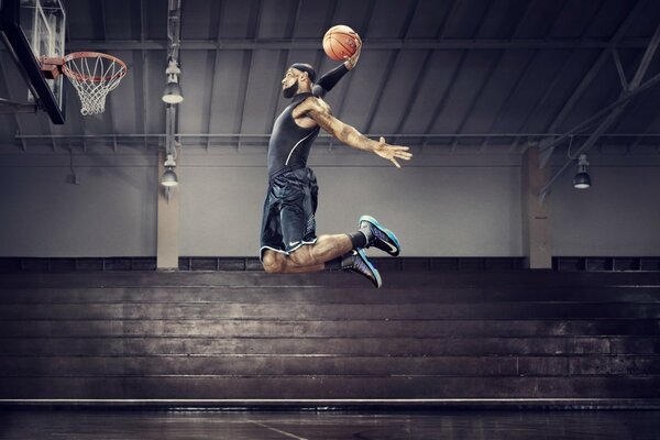 Basketball player with a ball in a jump in front of the ring