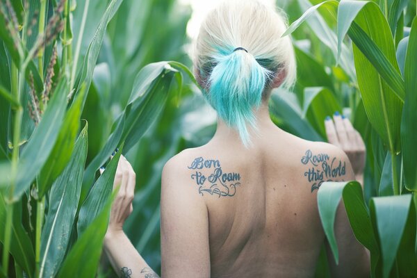 A girl with a tattoo and green hair in a cornfield