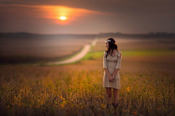 Fille dans un champ de fleurs au coucher du soleil