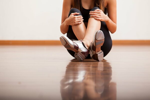 The girl is sitting on the floor, resting from dancing