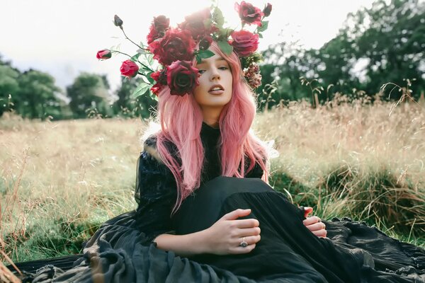 Mädchen im Feld mit Rosen auf dem Kopf