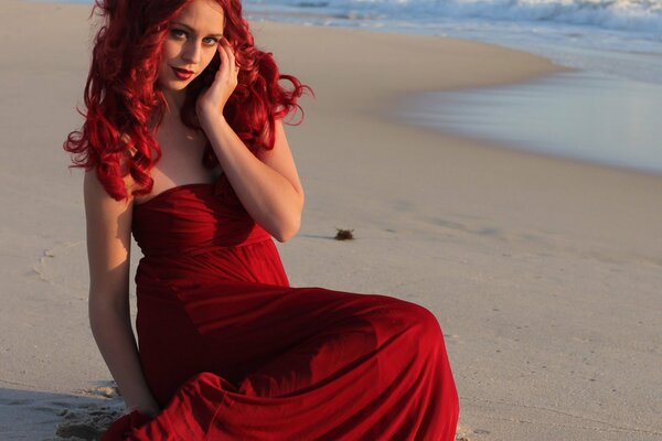 A girl in a red dress on the sand