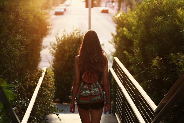 A girl with long hair with a small backpack on her back