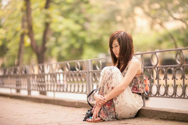 Asian girl sits thoughtfully in the park