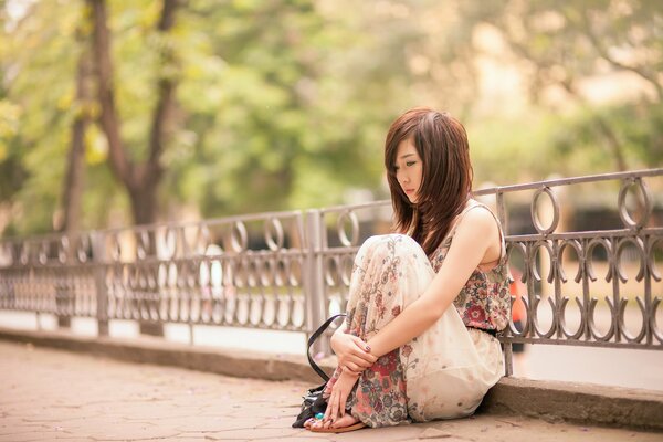 Chica asiática cuidadosamente sentado en el parque