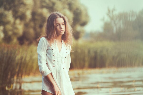 Fille triste en blouse blanche sur fond de plan d eau