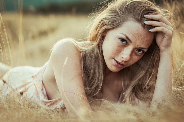 Olga Kobzar with freckles lies in a field