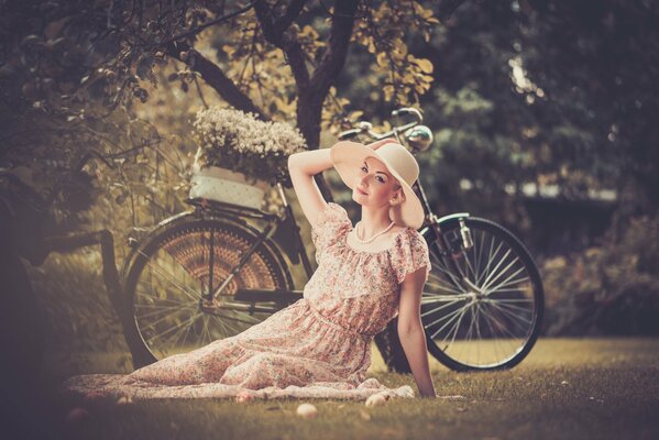 A girl in a hat is photographed with a bicycle