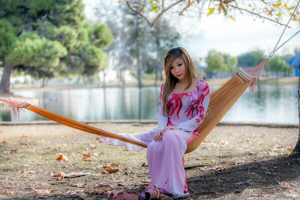 Chica sentada en una hamaca junto al lago