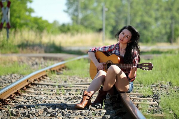 Linda chica con guitarra en los rieles