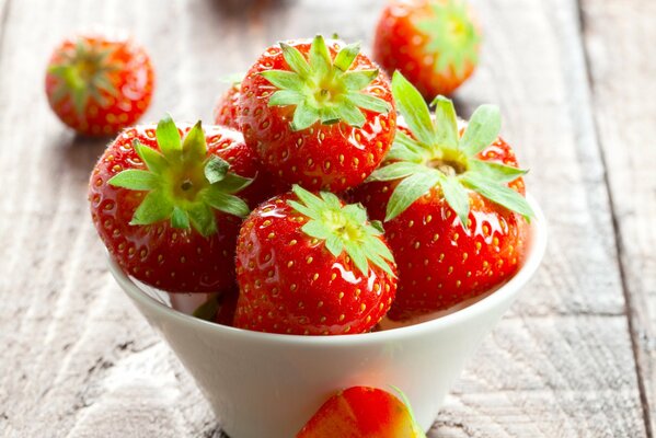 Red strawberries are lying in a bowl on the table