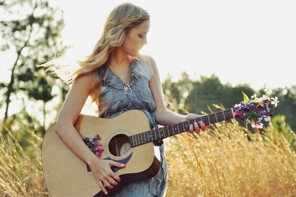 Slender girl with a guitar in nature