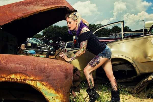 Girl with tattoos on the background of scrap metal