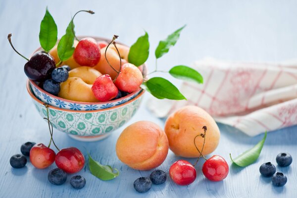 Still life of berries and fruits with bowls and napkin