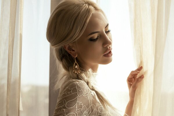 A beautiful girl is standing at the window