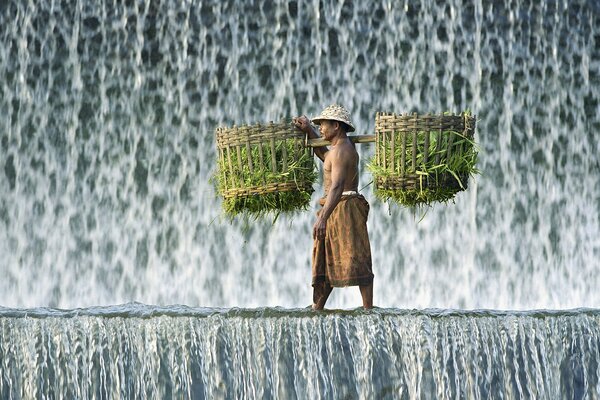 A man with a burden near a waterfall