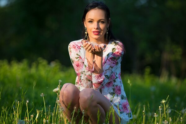 Süße Brünette in einem Kleid mit Blumen im Feld