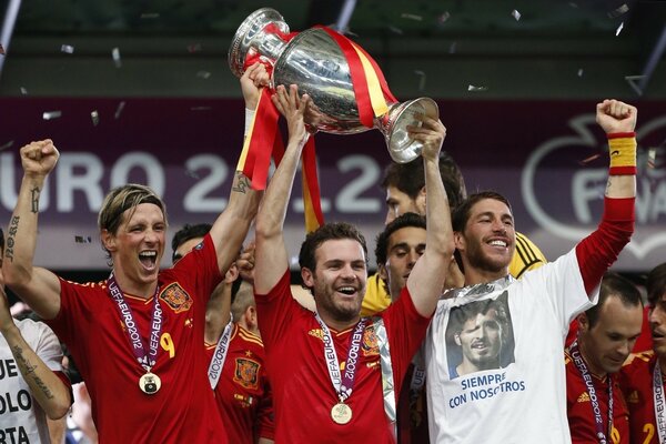 Fußballspieler mit Pokal in roter Uniform