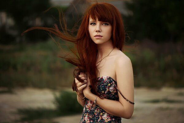 Redhead ragazza carina con i capelli in via di sviluppo e abito floreale