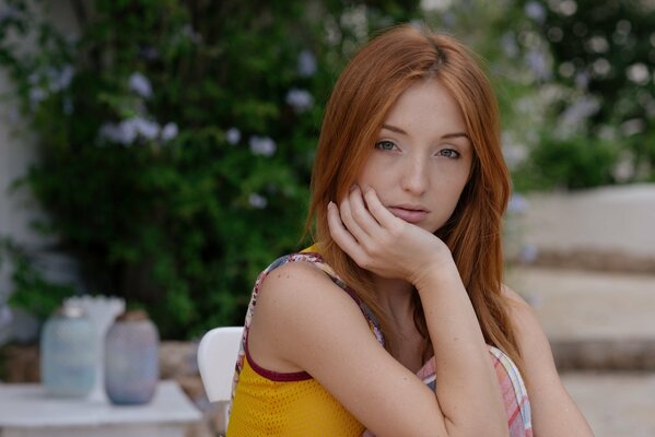 Redhead babe Natalie sullo sfondo di un arbusto fiorito