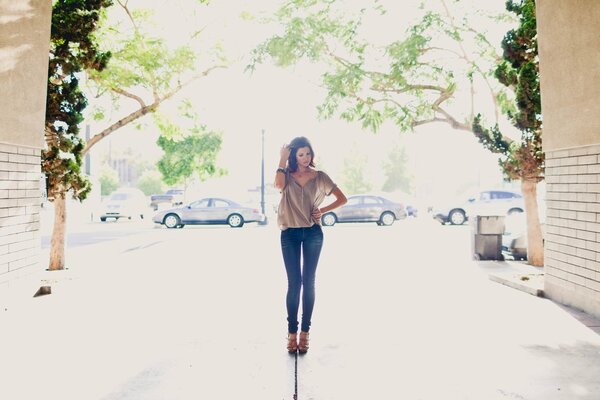 Ragazza in piedi nel cortile in camicetta e jeans