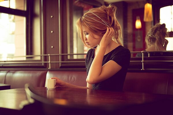 A girl in a cafe with a cup of coffee