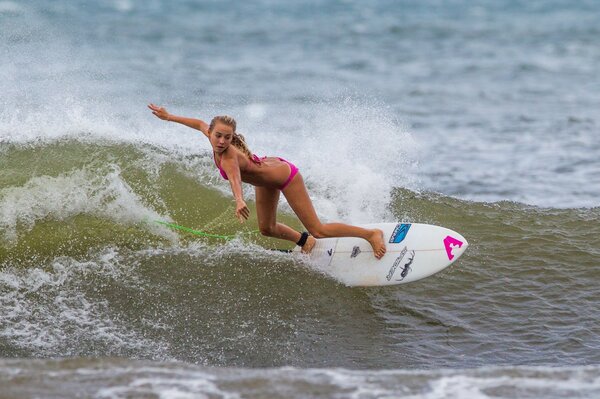A girl on a surfboard fights the waves